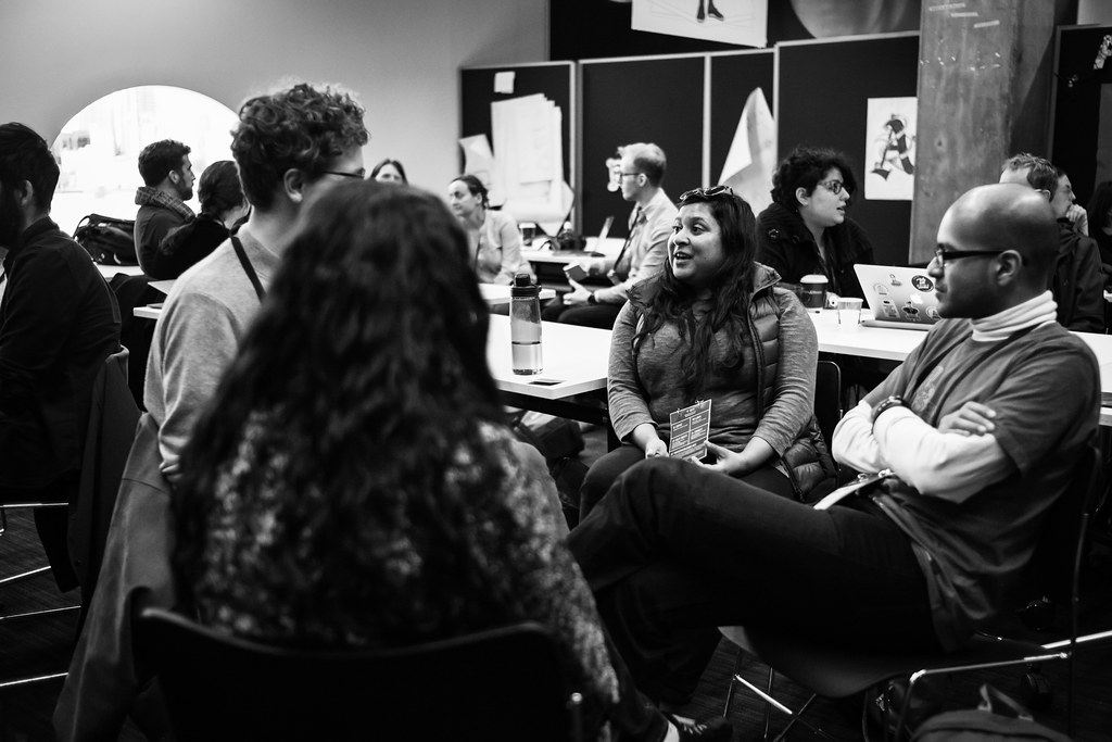 A discussion group talking around a table, in black and white